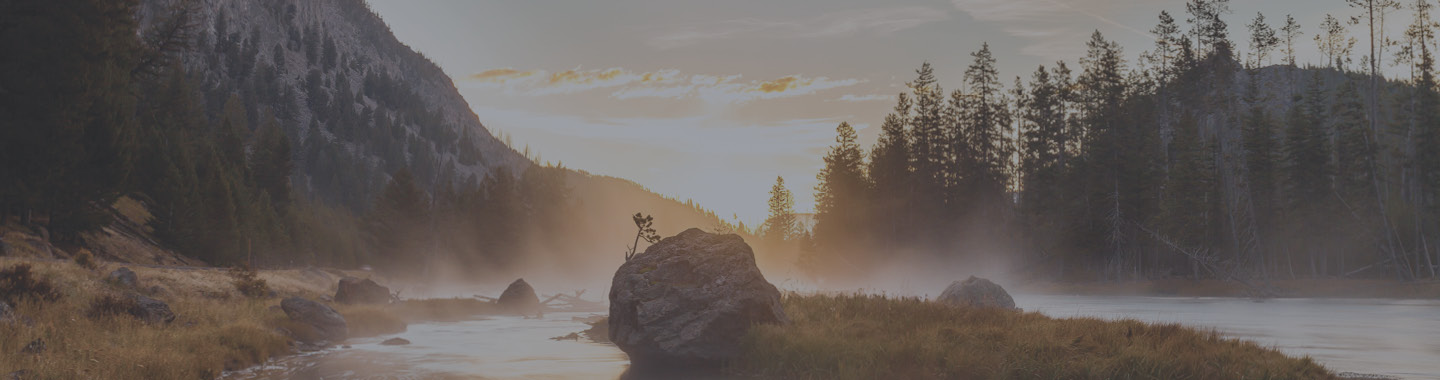 Image of the mountains and forest near a river at sunset.