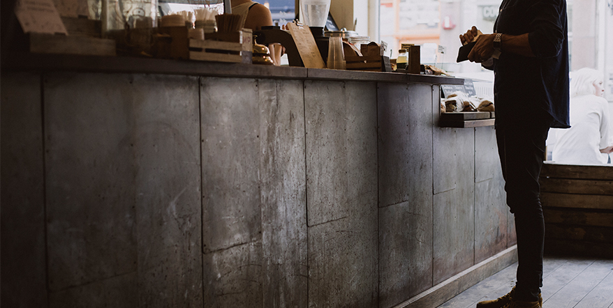 Image of man paying with a card at a coffee shop.