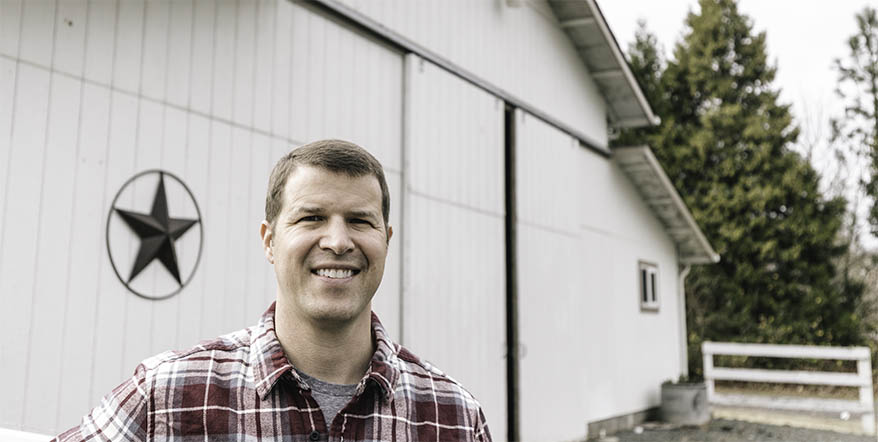 Image of Justin Buchanan in front of his renovated farmhouse.