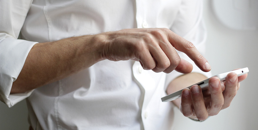 Image of man in white shirt using his smartphone.